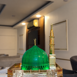 ساعة أذان رقمية بتصميم مستوحى من المسجد النبوي الشريف، تتميز بقبة خضراء مضاءة ومئذنة ذهبية مع شاشة عرض رقمية لمواقيت الصلاة والتاريخ