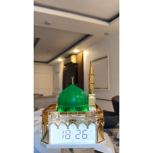 ساعة أذان رقمية بتصميم مستوحى من المسجد النبوي الشريف، تتميز بقبة خضراء مضاءة ومئذنة ذهبية مع شاشة عرض رقمية لمواقيت الصلاة والتاريخ