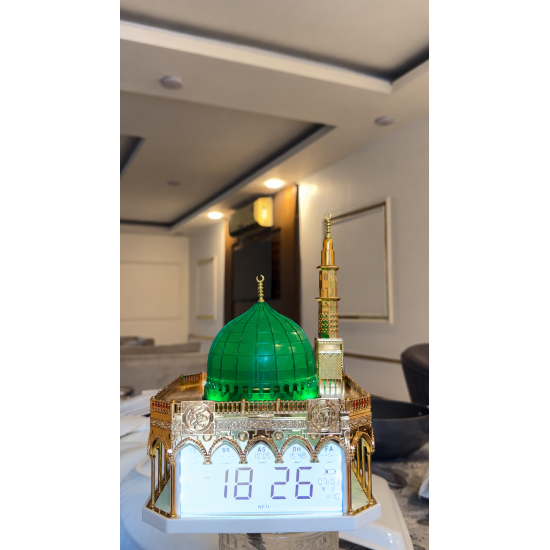 ساعة أذان رقمية بتصميم مستوحى من المسجد النبوي الشريف، تتميز بقبة خضراء مضاءة ومئذنة ذهبية مع شاشة عرض رقمية لمواقيت الصلاة والتاريخ